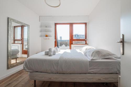 une chambre blanche avec un grand lit et un miroir dans l'établissement Panorama Cathédrale - Appt lumineux avec parking privé, à Strasbourg