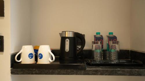 a coffee maker on a counter with cups and bottles at Zip By Spree Hotels Chinchwad in Chinchiwad