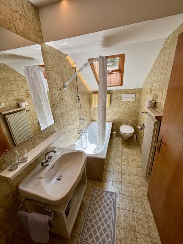 a bathroom with a sink and a tub and a toilet at Residence Linde - Ferienwohnungen & Apartments in Castelrotto