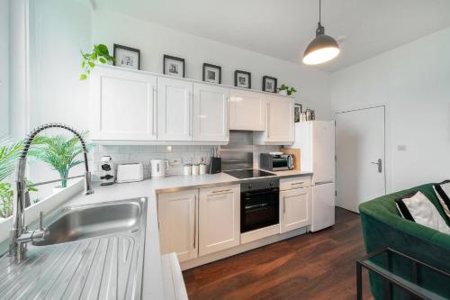 a kitchen with white cabinets and a stainless steel sink at Princess Street Studios in Dundee