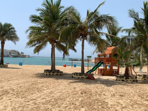 a playground on a beach with palm trees and the ocean at شاليه الحمرا 2-12بدرة العروس in Jeddah