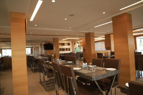 a restaurant with a long table and chairs at Hotel JD in Surat