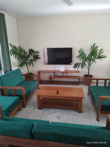 a living room with green furniture and a flat screen tv at Casa Nampala 2bedrom units in Ukunda