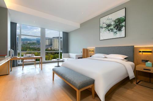 una camera da letto con un grande letto bianco e una grande finestra di SSAW Boutique Hotel Zhijiang a Hangzhou