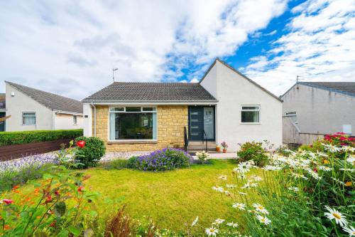 a white house with a yard with flowers at Newhall Gardens in Invergowrie