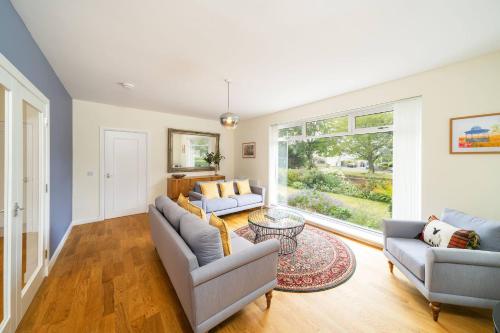 a living room with two couches and a large window at Newhall Gardens in Invergowrie