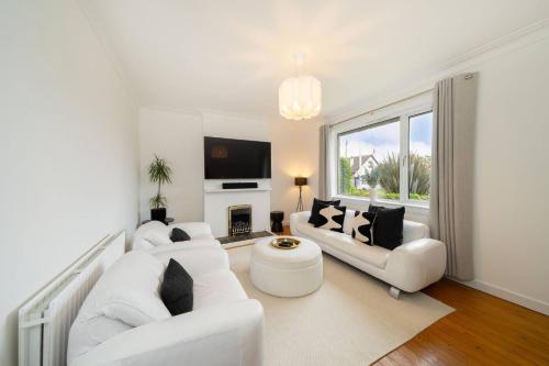 a white living room with two white couches and a fireplace at Taigh Tatha in Broughty Ferry