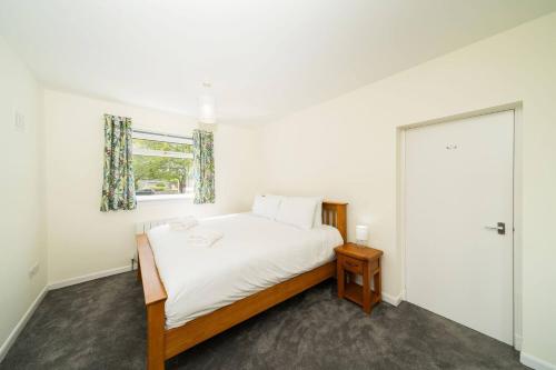 a white bedroom with a bed and a window at Newhall Gardens in Invergowrie