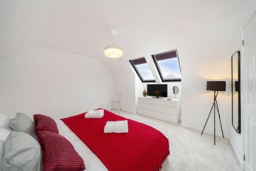 a white bedroom with a red blanket on a bed at Taigh Tatha in Broughty Ferry