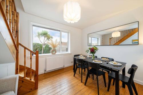 a dining room with a black table and chairs at Taigh Tatha in Broughty Ferry