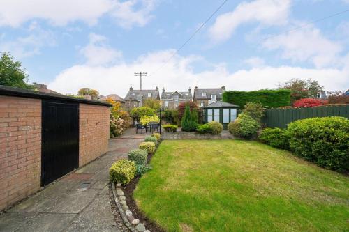 a backyard with a yard with a brick wall at Taigh Tatha in Broughty Ferry