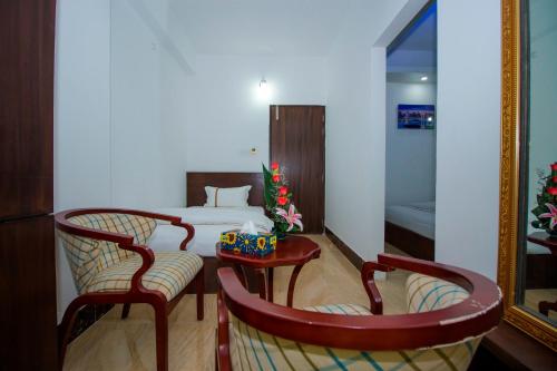a room with a bed and two chairs and a mirror at Hotel Progati Inn Ltd. in Dhaka