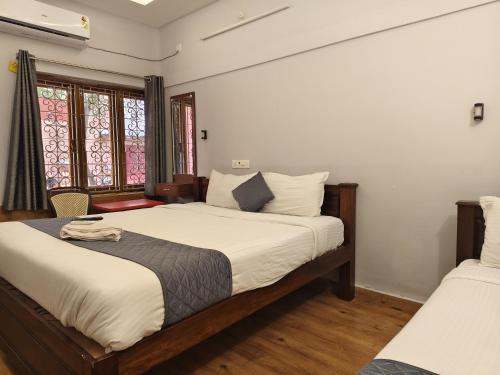 a bedroom with two beds and two windows at Lax Residency, White Town, Pondicherry in Puducherry