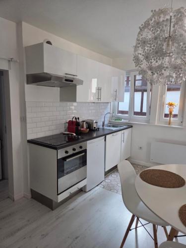 - une cuisine blanche avec une cuisinière et une table dans l'établissement Escapade atypique à 2 pas de la Cathédrale, à Strasbourg