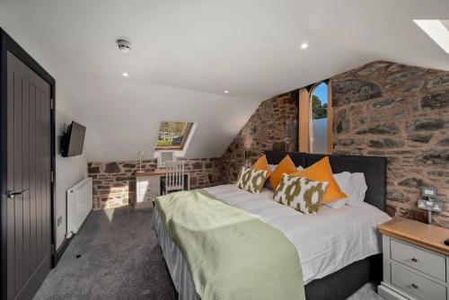 a bedroom with a bed and a stone wall at The Stables in Dundee