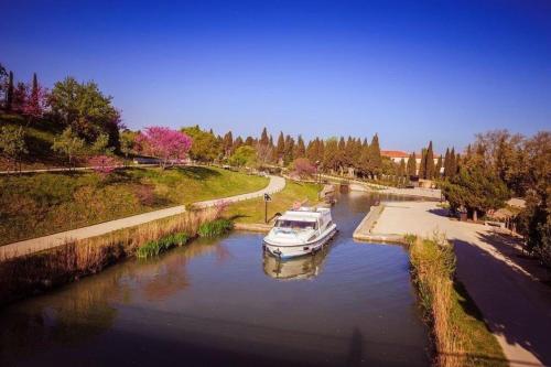 a boat is docked in a river near a road at Chambres d'hôtes Sauvian in Sauvian