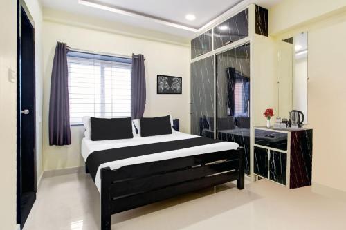 a bedroom with a black and white bed and a window at Super Hotel O Murali Nagar Near NAD Junction in Visakhapatnam