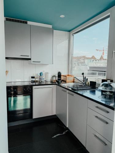 a kitchen with white cabinets and a large window at Just Sunny - Rooftop mitten in der Stadt in Basel