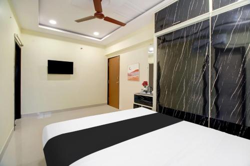 a bedroom with a black and white bed and a tv at Super Hotel O Murali Nagar Near NAD Junction in Visakhapatnam