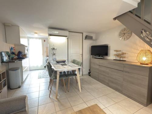 une cuisine avec une table et une télévision. dans l'établissement Petite maison avec jardin & piscine partagee, à Valras-Plage
