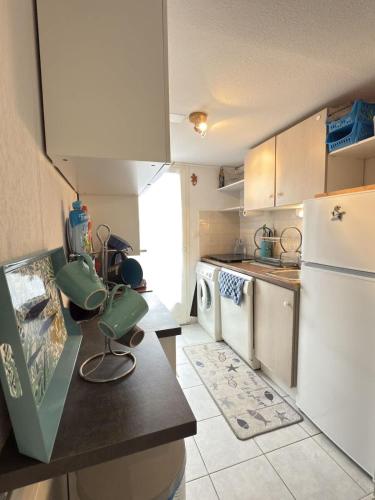 Il comprend une cuisine équipée d'un réfrigérateur blanc et d'une cuisinière. dans l'établissement Petite maison avec jardin & piscine partagee, à Valras-Plage