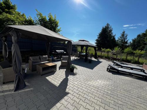 a patio with umbrellas and furniture on a patio at Do Brzegu Lepiej - Siedlisko Jemiołowo - Apartamenty Blisko Jeziora in Olsztynek
