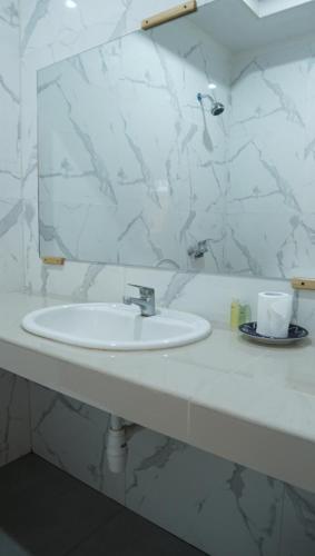 a white bathroom with a sink and a mirror at Grand Desa Resort in Cimaja