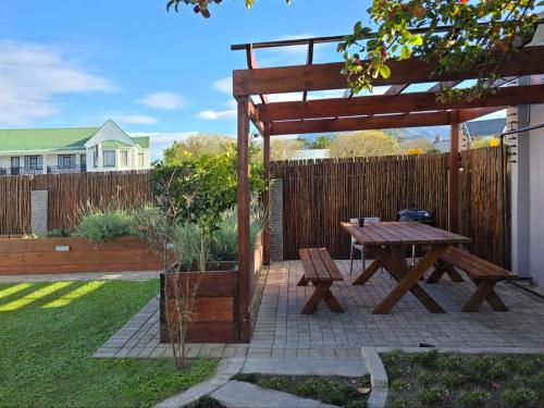 a picnic table and a wooden pergola in a yard at Breathe Inn in George