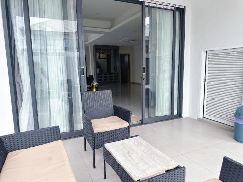 a balcony with chairs and a table and glass doors at Eakmongkol Luxury Five-Bedroom Pool Villa in Jomtien Beach