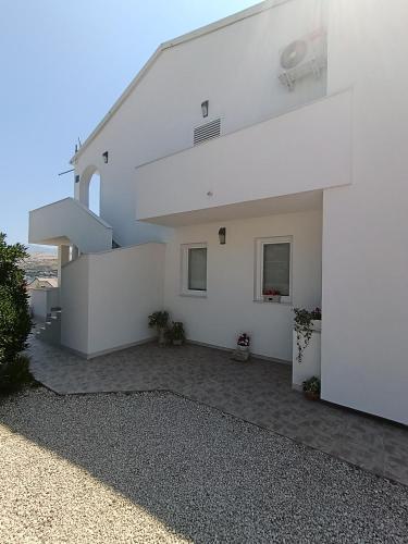 a white house with a staircase on the side of it at Apartments Višnja in Pag