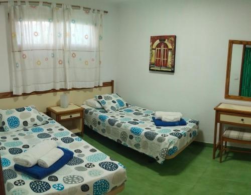 a room with two beds and a table and a mirror at Aguycan - Bungalow with ocean views in San Bartolomé de Tirajana