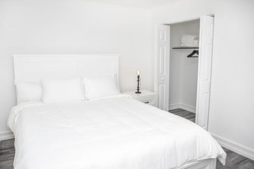 Un dormitorio blanco con una cama blanca y una puerta. en Location! Quality! Comfort! The downtown Gem, en Naples