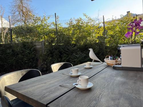 a wooden table with cups and a bird sitting on it at Marcel Cahen 5 Luxurious Home for Families Groups and Events in Luxembourg