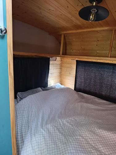 un lit dans une chambre avec un plafond en bois dans l'établissement la cabane mobile, à Beyssenac