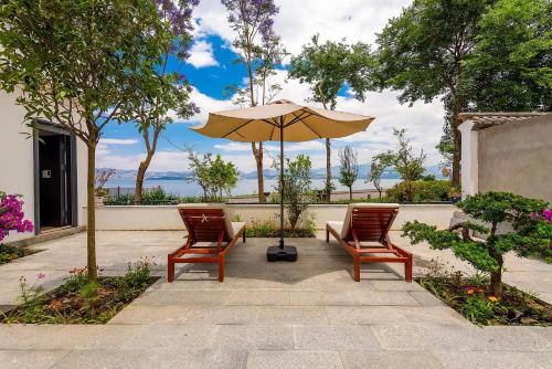 a patio with two chairs and an umbrella at Dali Blue House Sea View B&B in Dali Ancient Town