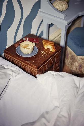 a bed with a table with a cup of coffee on it at Hotel Ruth, WorldHotels Crafted in Stockholm