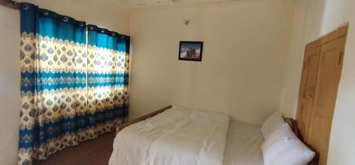 a small bedroom with a bed and a window at Hunza Backpacker Inn in Karimabad Hunza