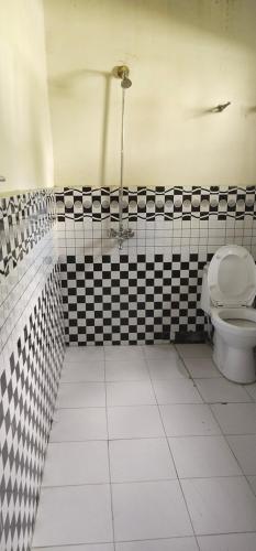 a bathroom with a toilet and black and white tiles at Hunza Backpacker Inn in Karimabad Hunza