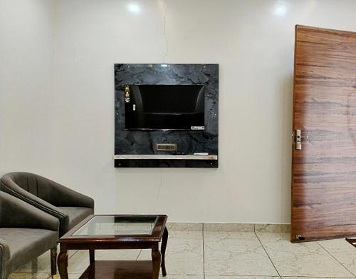 a living room with a couch and a tv on a wall at Hotel sky heights in Sonīpat