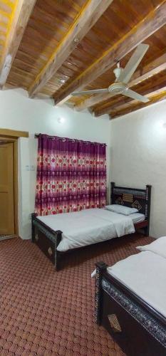 a bedroom with two beds and a ceiling fan at Hunza Backpacker Inn in Karimabad Hunza