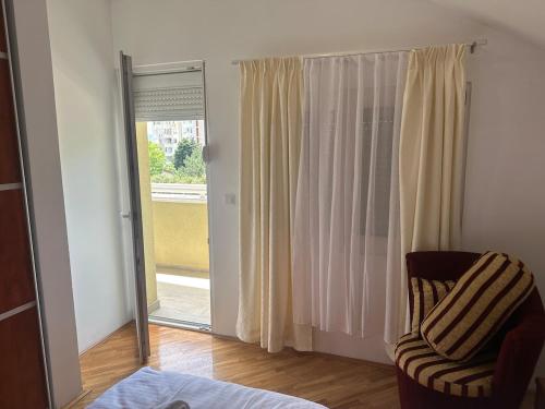 a living room with a chair and a sliding glass door at Apartments Naresi Mostar in Mostar