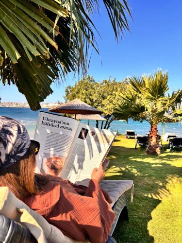 a woman sitting in a chair reading a newspaper at Şato Design Hotel in Cesme