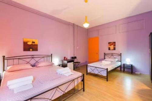 two beds in a room with purple walls at Acropolis psiri budget rooms in Athens