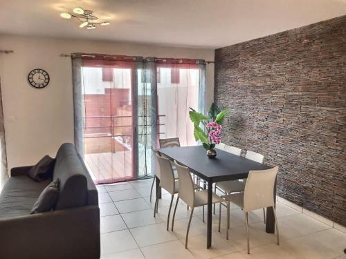 d'une salle à manger avec une table, des chaises et un mur en briques. dans l'établissement ROY ld70, à Sérignan