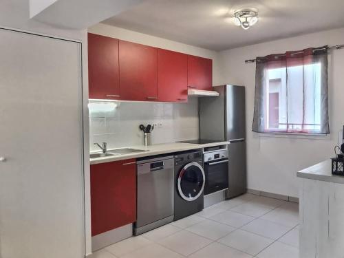 - une cuisine avec des placards rouges et un lave-linge dans l'établissement ROY ld70, à Sérignan