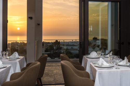 a restaurant with tables and chairs and a view of the ocean at Kefalos Damon Hotel Apartments in Paphos City