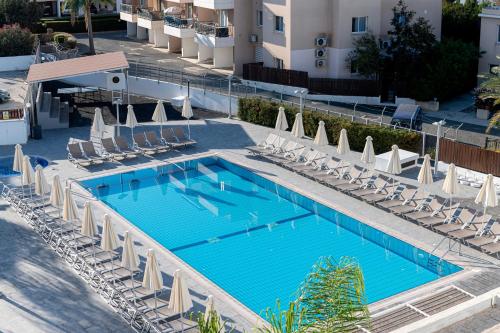 an overhead view of a swimming pool with chairs and umbrellas at Kefalos Damon Hotel Apartments in Paphos City