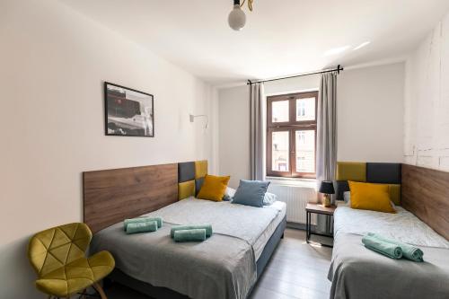 a bedroom with two beds and a chair at Cooltour Hostel in Poznań