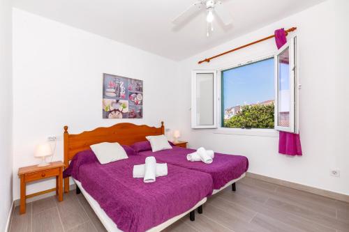 a bedroom with a bed with purple sheets and a window at Apartamento Biniforcat in Cala en Forcat