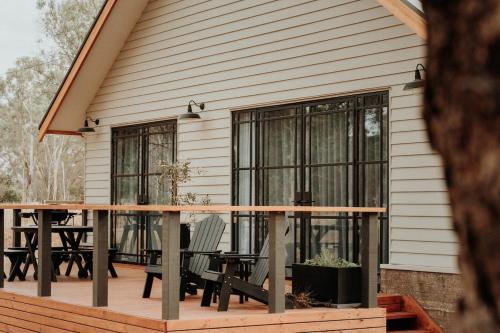 a house with a deck with chairs and a table at The Barn - On Cockatoo Lane in Sandy Creek